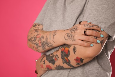 Photo of Woman with tattoos on arms against pink background, closeup