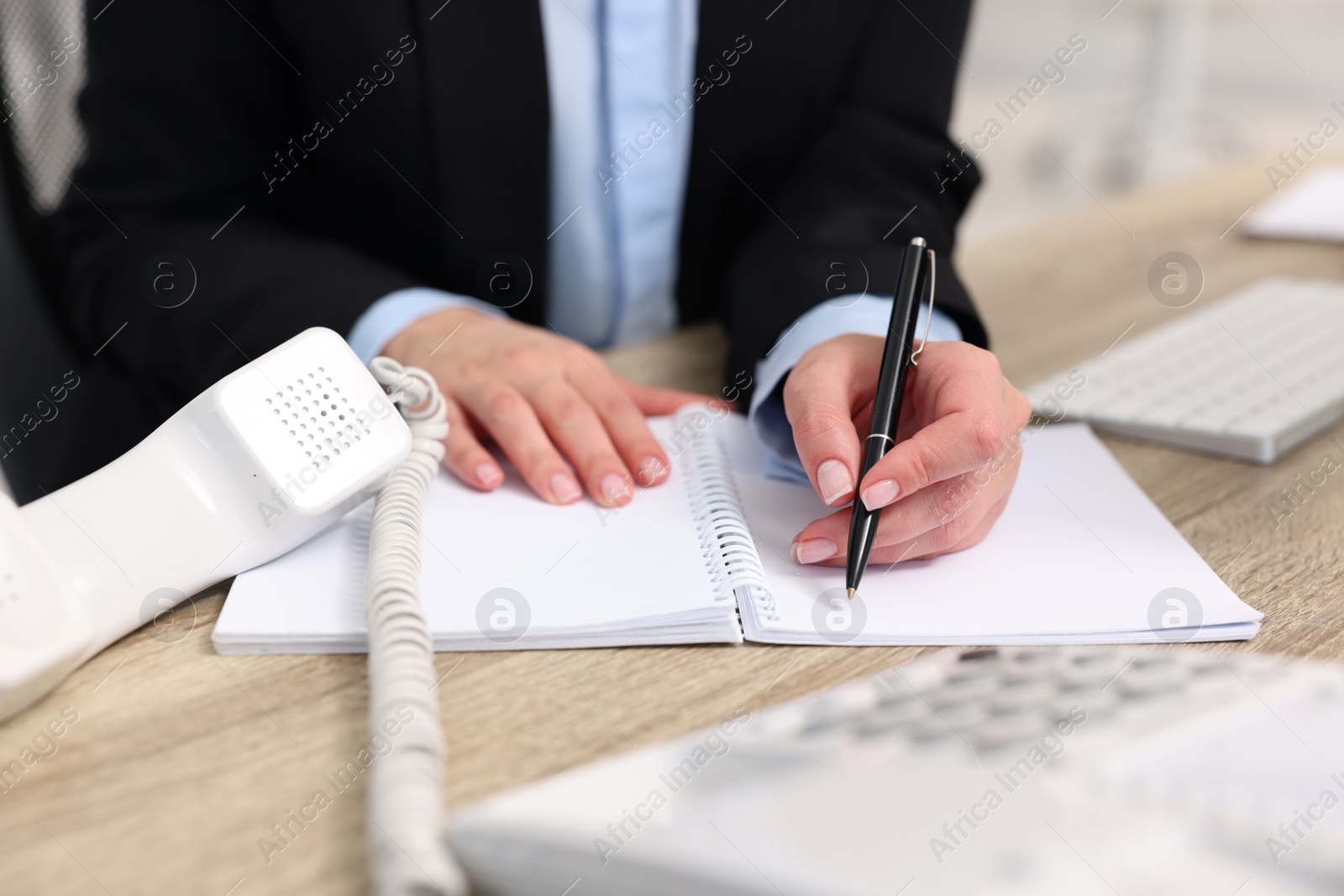 Photo of Secretary writing something at table in office, closeup
