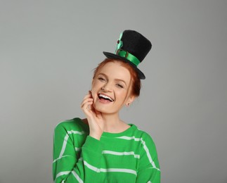 Image of St. Patrick's day party. Pretty woman in leprechaun hat on grey background