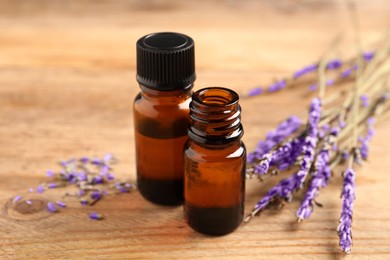 Essential oil and lavender flowers on wooden table, closeup