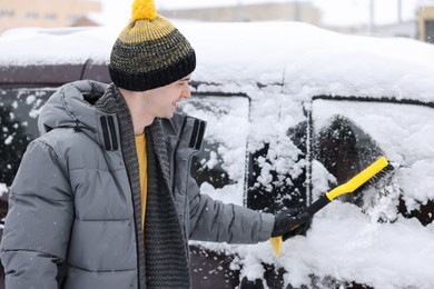 Man cleaning snow from car window outdoors