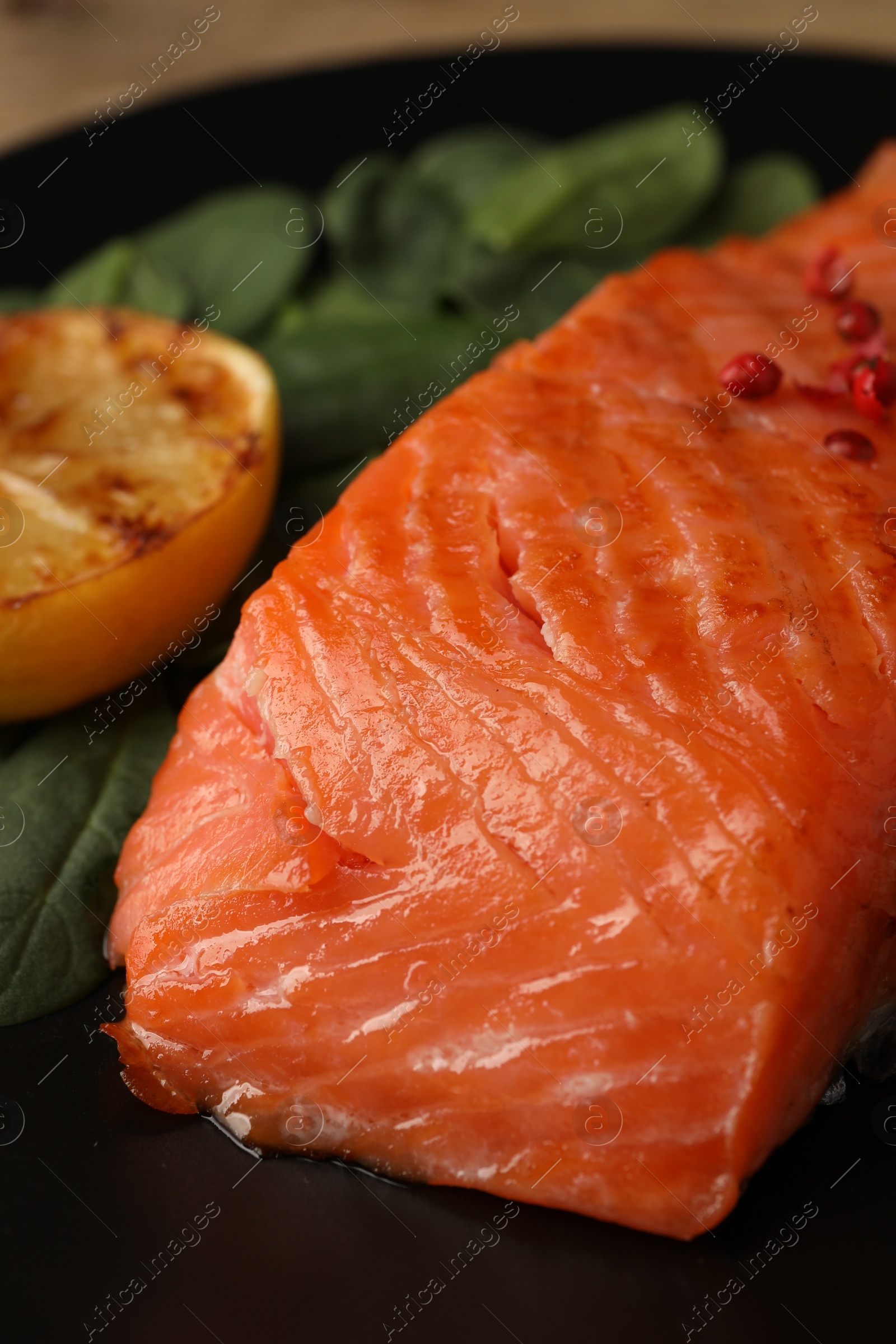 Photo of Tasty grilled salmon with lemon and basil on plate, closeup