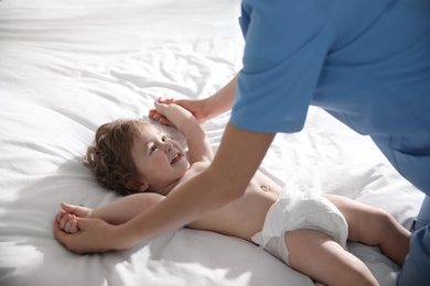 Orthopedist examining cute little baby on bed