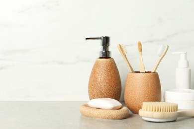 Different bath accessories and personal care products on gray table near white marble wall, space for text