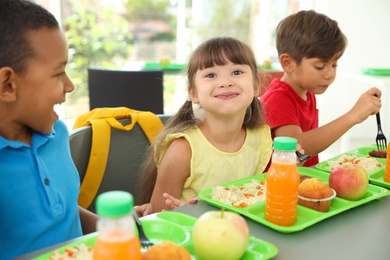 Children sitting at table and eating healthy food during break at school