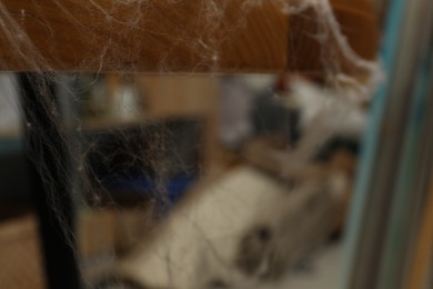 Photo of Old cobweb on wooden table indoors, closeup