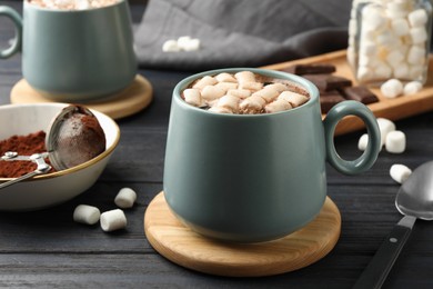 Photo of Cup of aromatic hot chocolate with marshmallows served on dark gray wooden table, closeup