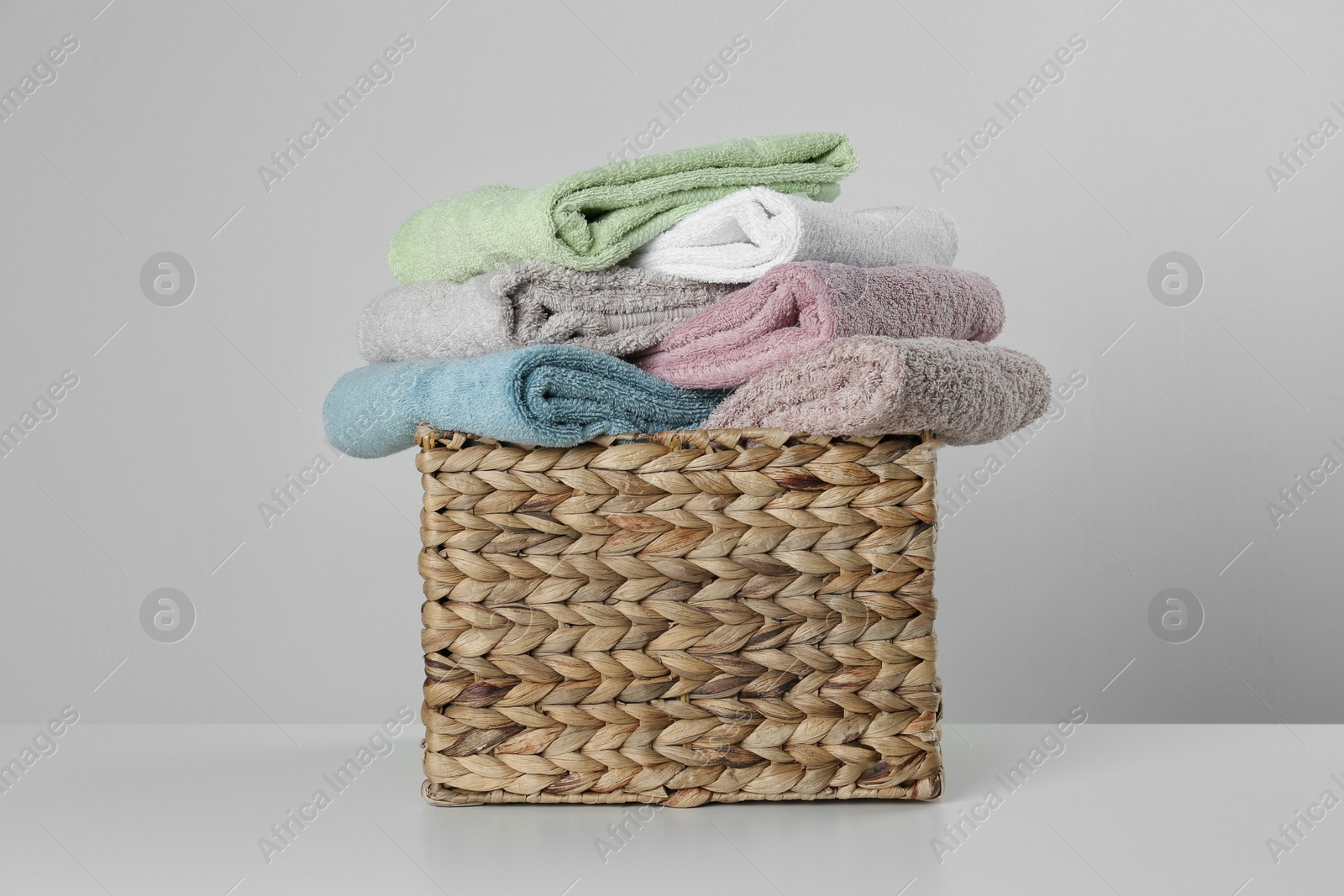 Photo of Wicker basket with clean soft towels on light background