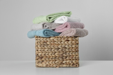Photo of Wicker basket with clean soft towels on light background