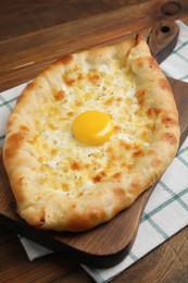 Photo of Fresh homemade khachapuri with cheese and egg on wooden table
