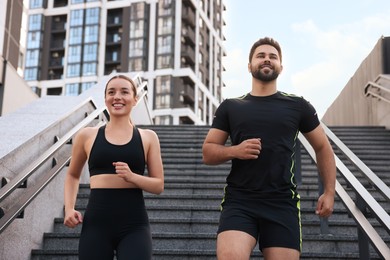 Healthy lifestyle. Happy couple running on steps outdoors, low angle view