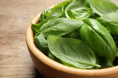 Photo of Fresh basil leaves on wooden table, closeup