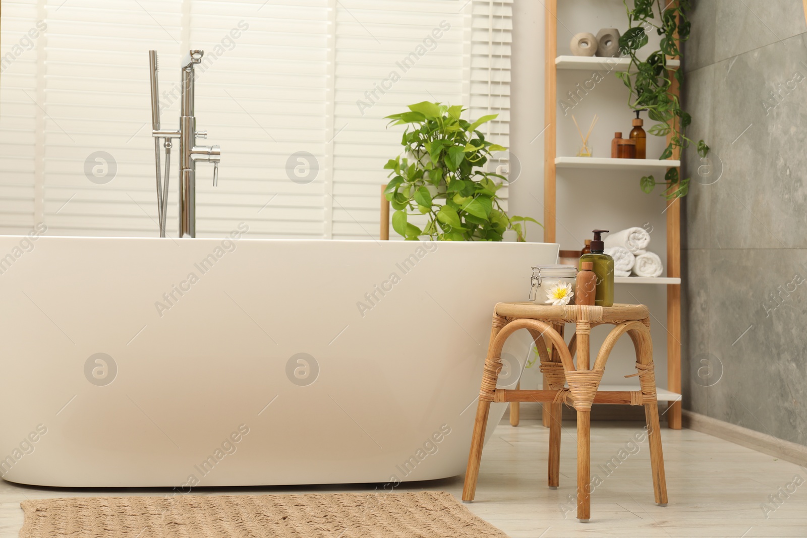 Photo of Stylish bathroom interior with ceramic tub, spa products and green houseplants