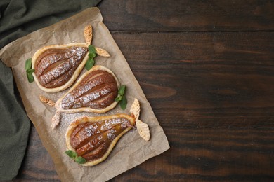 Delicious pears baked in puff pastry with powdered sugar and mint on wooden table, top view. Space for text