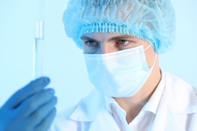 Photo of Scientist working with sample on light blue background, closeup. Medical research