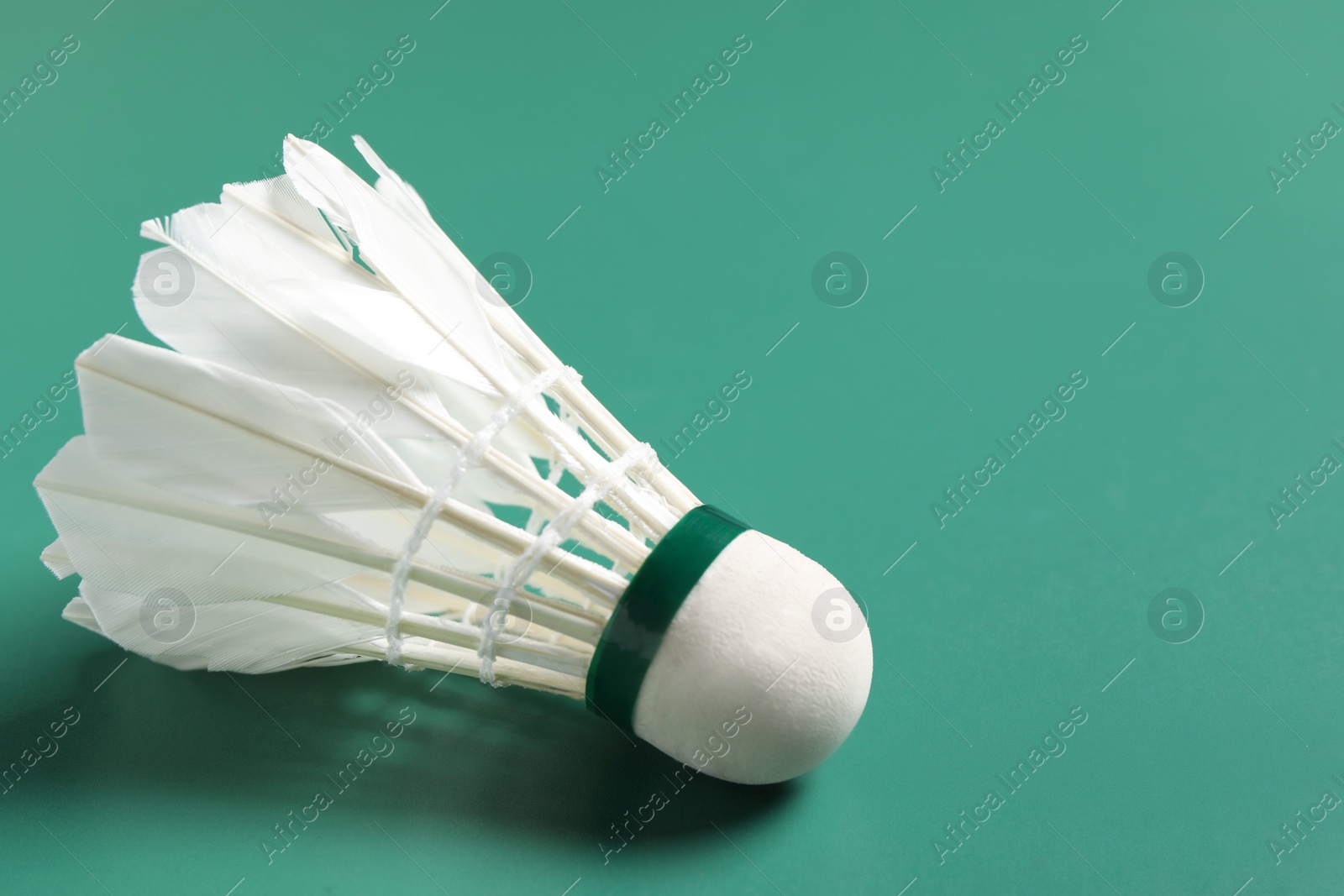 Photo of Feather badminton shuttlecock on green background, closeup. Space for text