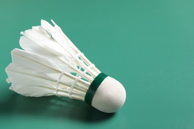 Photo of Feather badminton shuttlecock on green background, closeup. Space for text