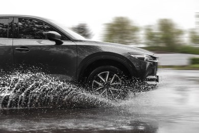 Image of Black car driving through puddle at high speed on rainy day, motion blur effect