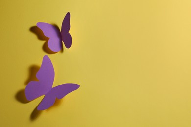 Bright purple paper butterflies on yellow background