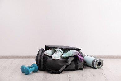 Photo of Grey bag and sports accessories on floor near white wall, space for text
