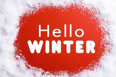 Image of Greeting card. Snow around text Hello Winter on red background, top view