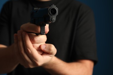 Photo of Man holding gun on dark background, closeup