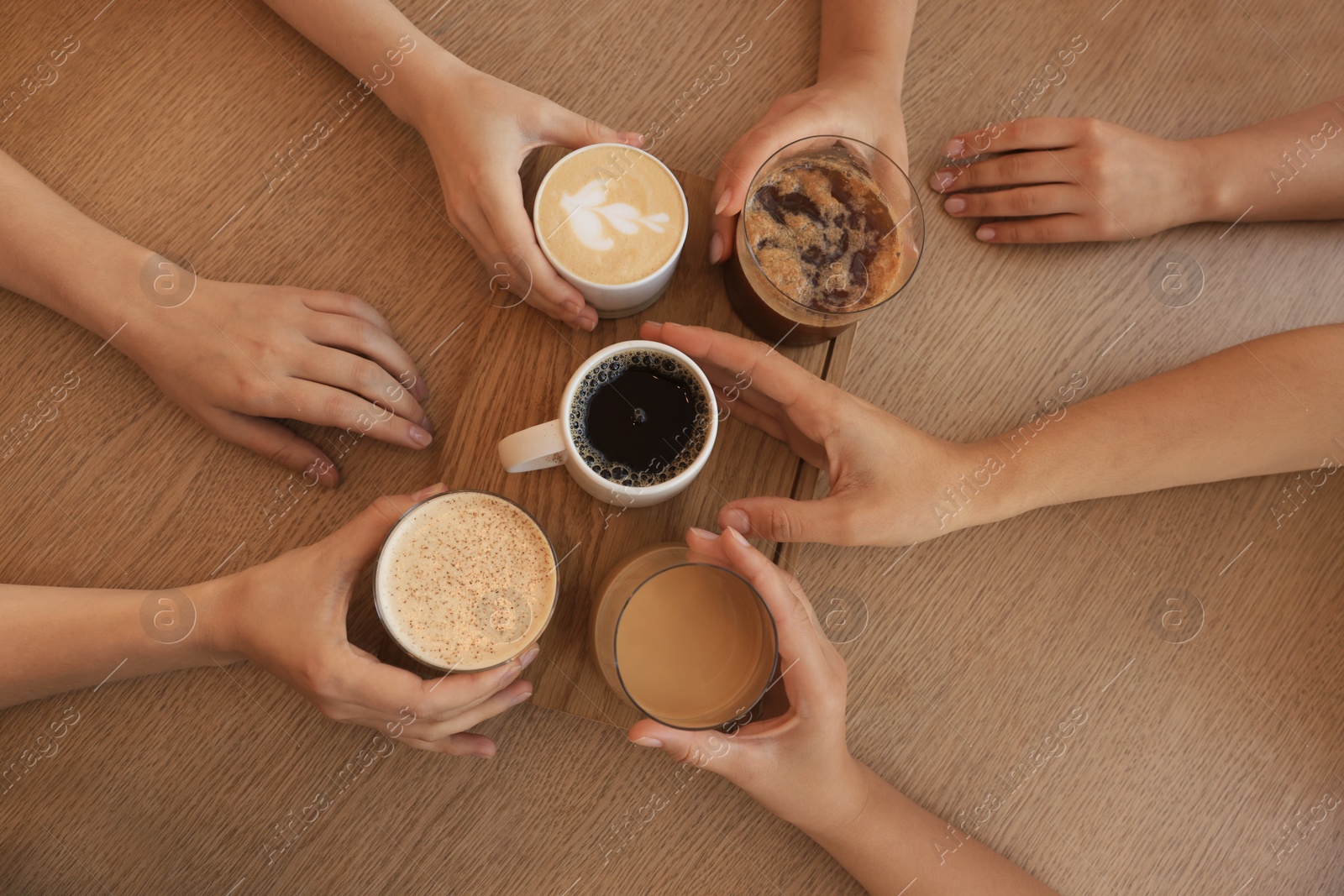 Photo of Friends drinking coffee at wooden table in cafe, top view