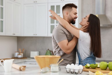 Photo of Affectionate young couple spending time together in kitchen. Space for text