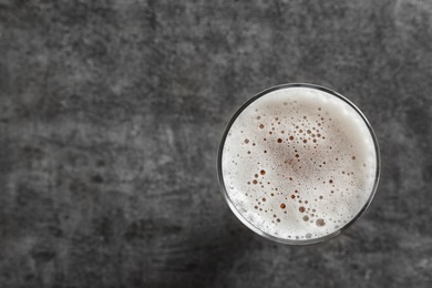 Photo of Glass with cold tasty beer on grunge background, top view