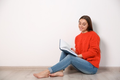 Photo of Young woman reading book on floor near wall, space for text