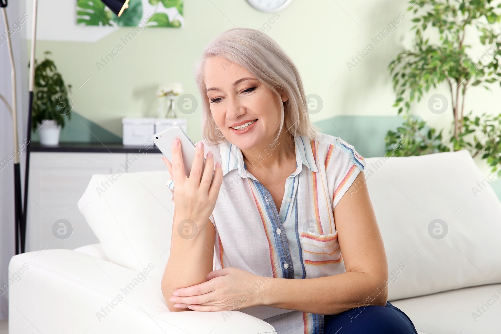 Photo of Mature woman using mobile phone at home