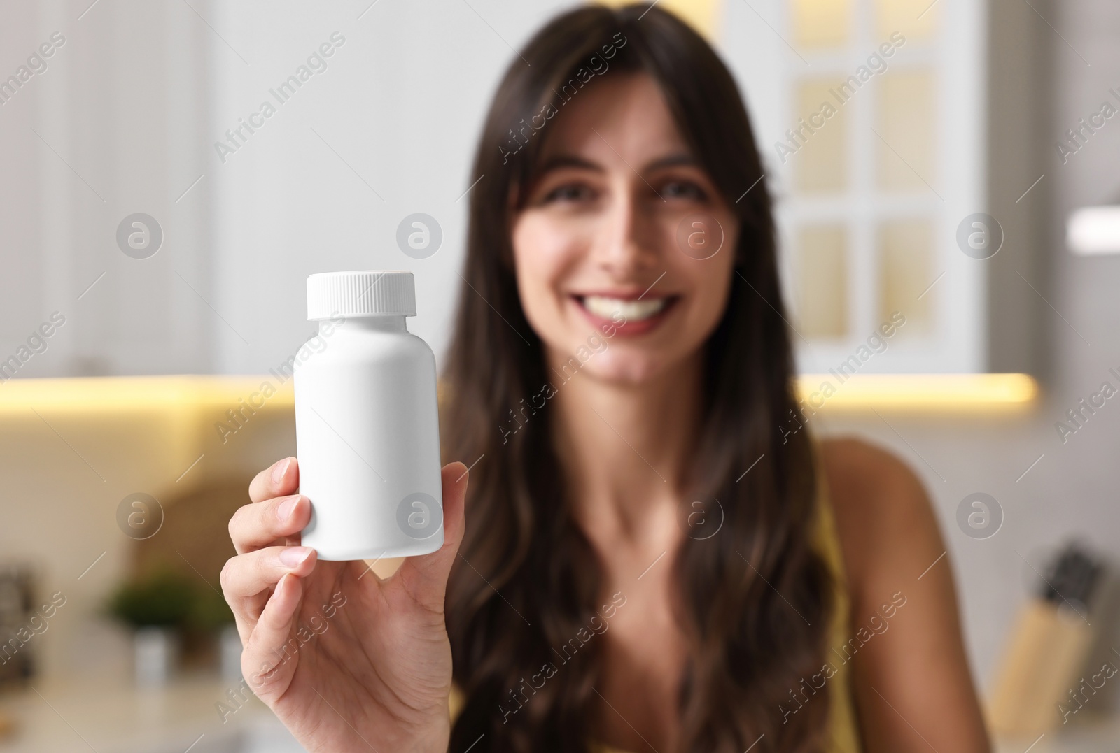 Photo of Beautiful woman with bottle of vitamin pills at home, selective focus