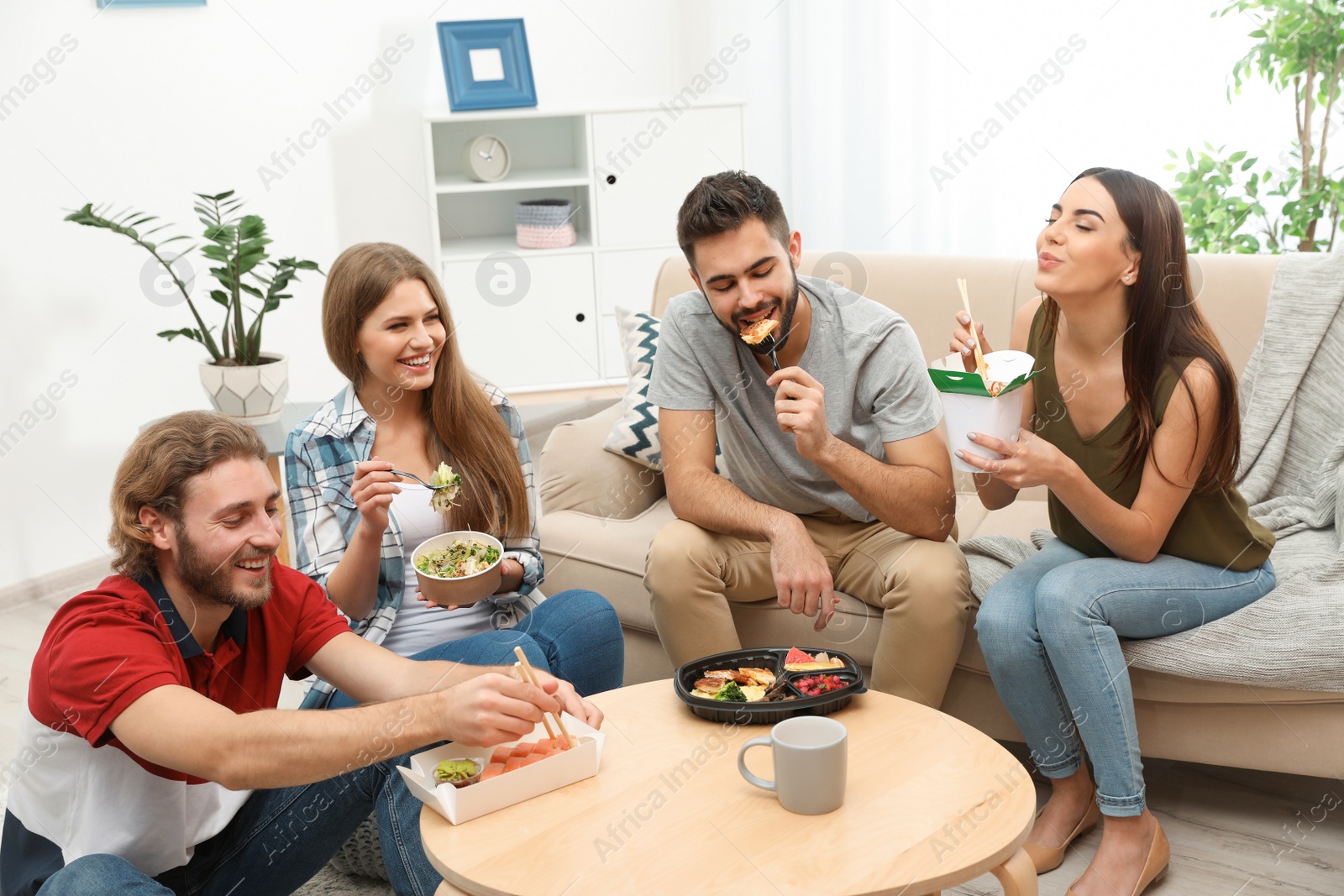 Photo of Young people having lunch together in living room. Food delivery