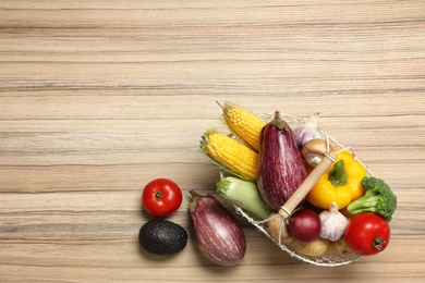 Photo of Basket with different fresh vegetables on wooden background, top view