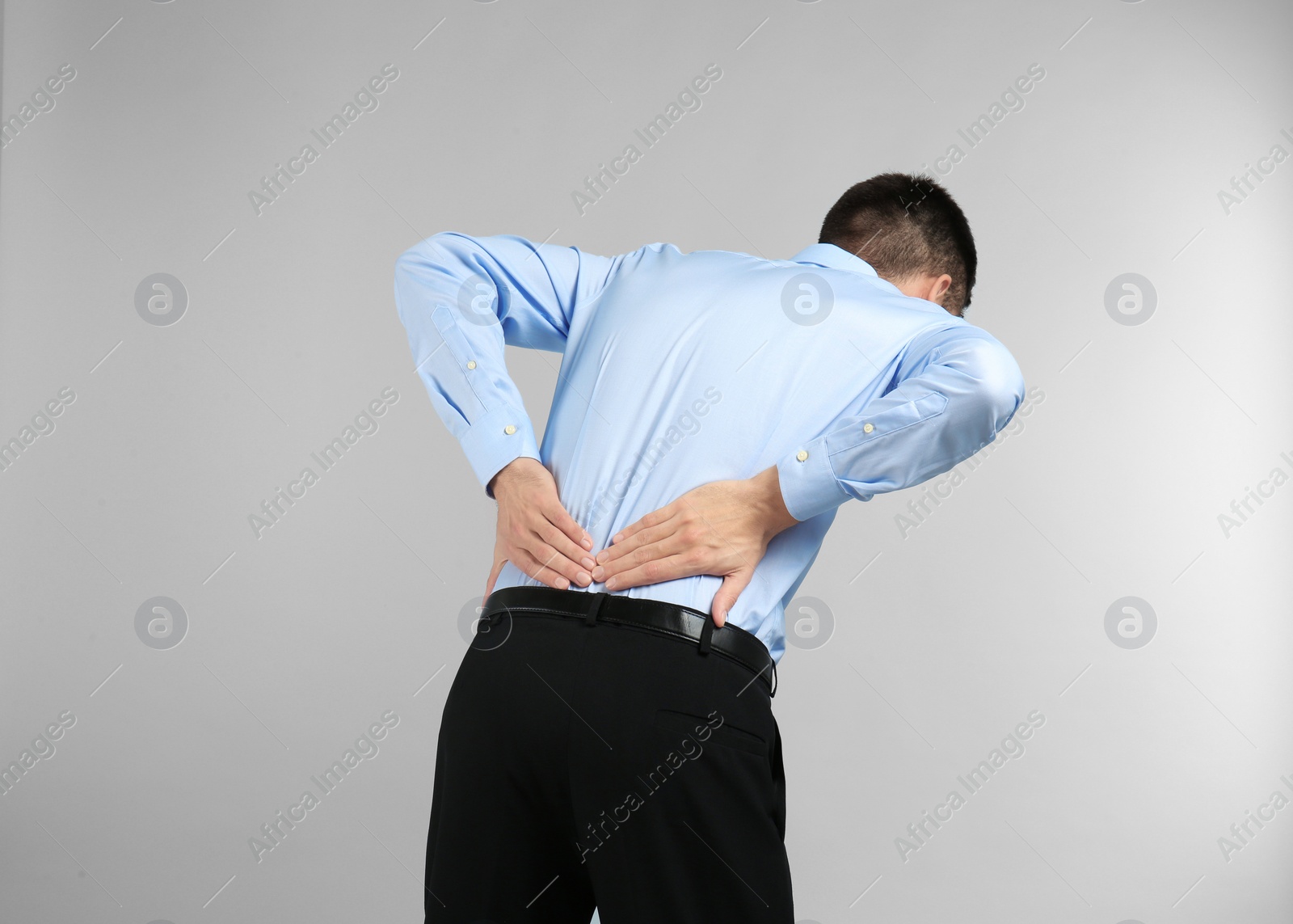Photo of Young man suffering from back pain on light background