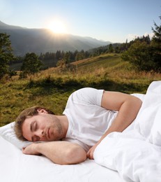 Man sleeping in bed and beautiful view of mountain landscape on background. Sleep well - stay healthy