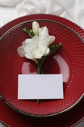 Dishes with blank card and flower on table, top view