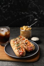 Delicious hot dogs with bacon, carrot and parsley served on grey table