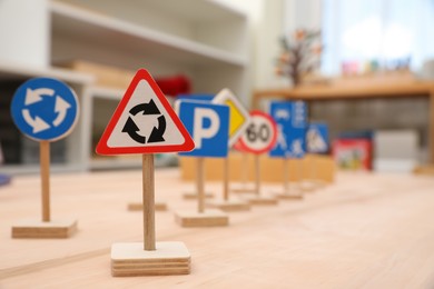 Photo of Different miniature road signs on wooden table, space for text. Montessori toy