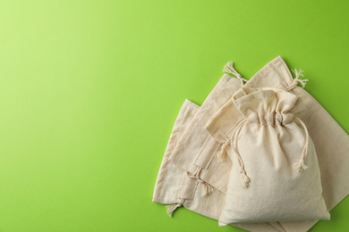 Photo of Cotton eco bags on light green background, flat lay. Space for text