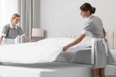 Photo of Professional chambermaids making bed in hotel room
