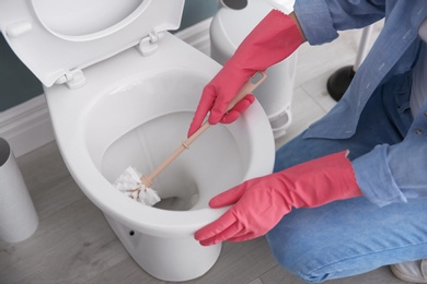 Woman cleaning toilet bowl in bathroom