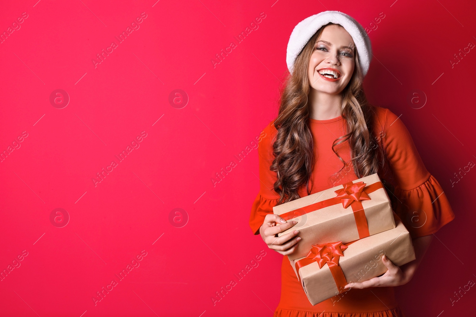 Photo of Beautiful young woman in Santa hat with gift boxes on color background. Christmas celebration