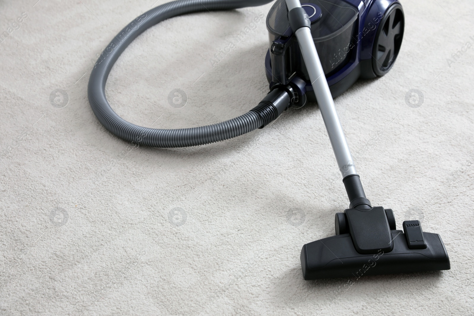 Photo of Modern vacuum cleaner on carpet indoors. Space for text