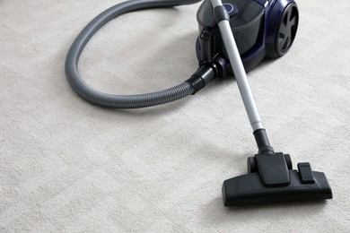 Photo of Modern vacuum cleaner on carpet indoors. Space for text