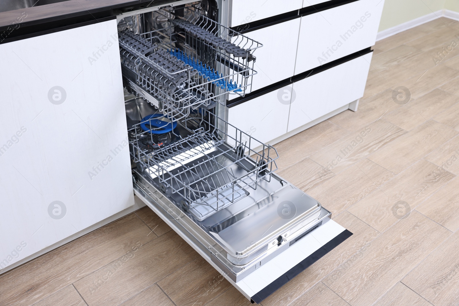 Photo of Open clean empty dishwasher in kitchen. Home appliance