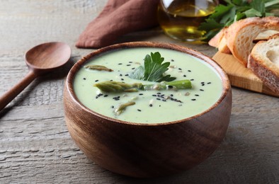 Photo of Bowl of delicious asparagus soup on wooden table