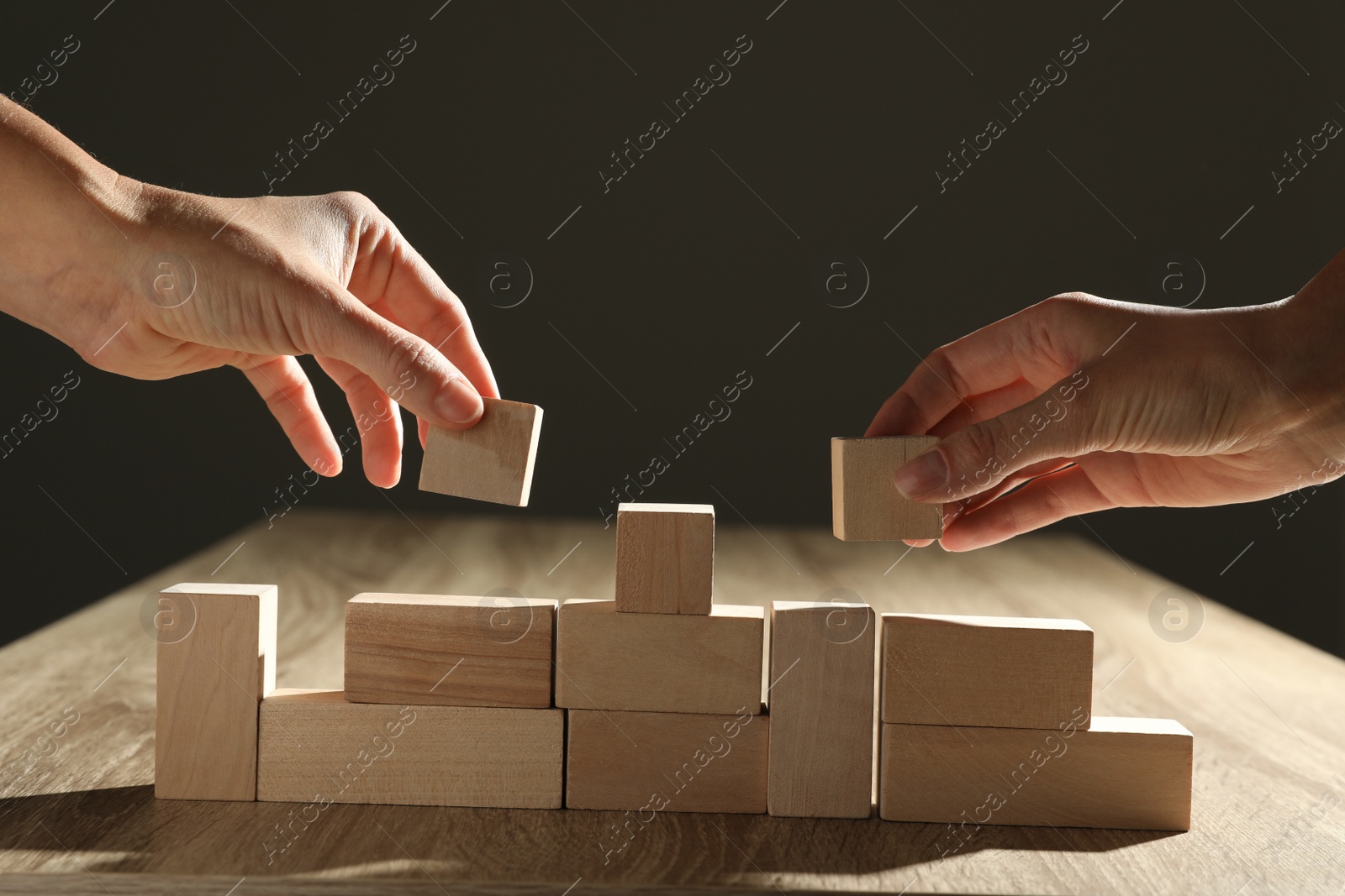 Photo of People constructing with wooden building blocks, closeup. Corporate social responsibility concept