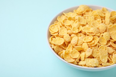 Photo of Breakfast cereal. Tasty corn flakes in bowl on light blue table, closeup. Space for text