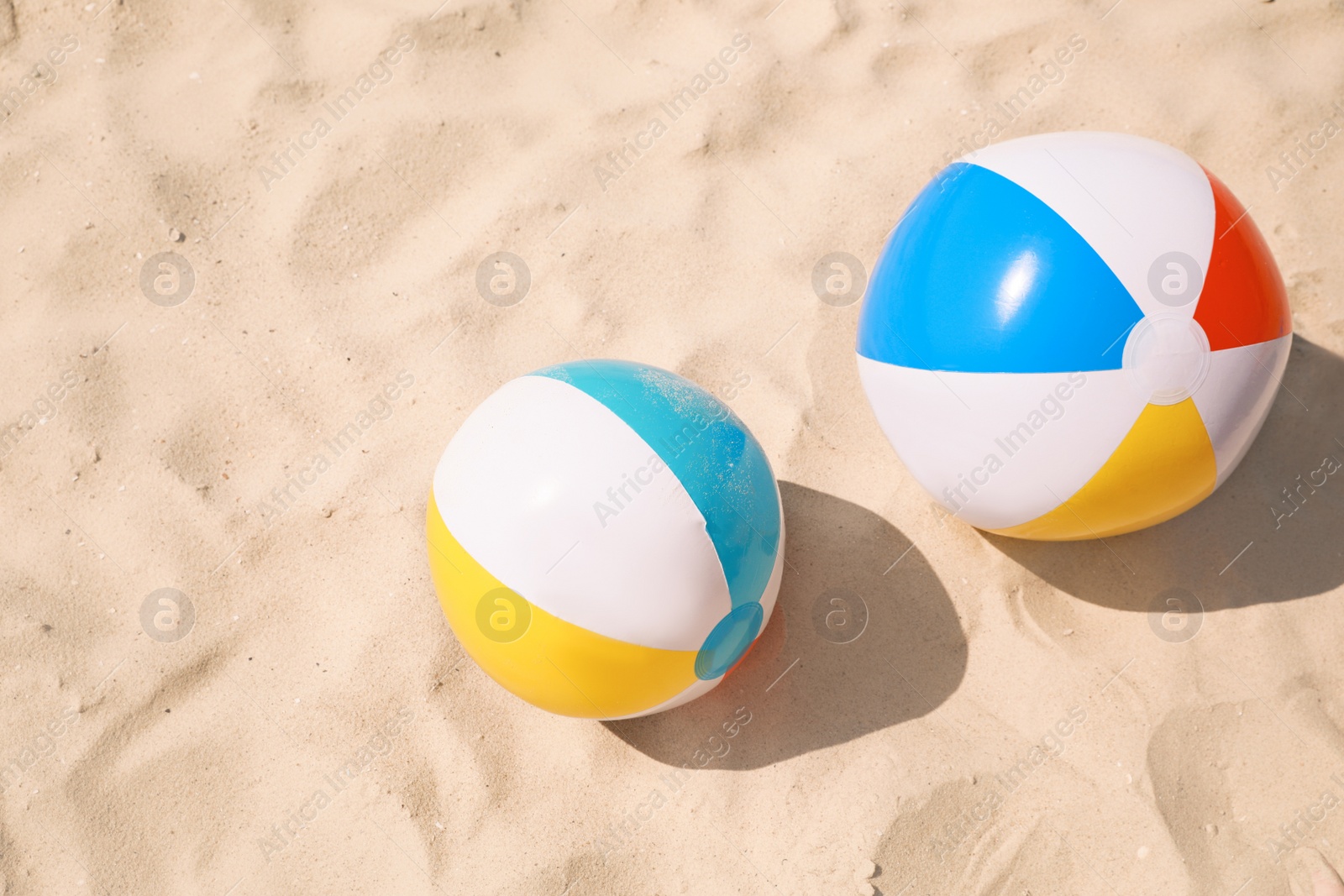 Photo of Bright beach balls on sand outdoors, above view